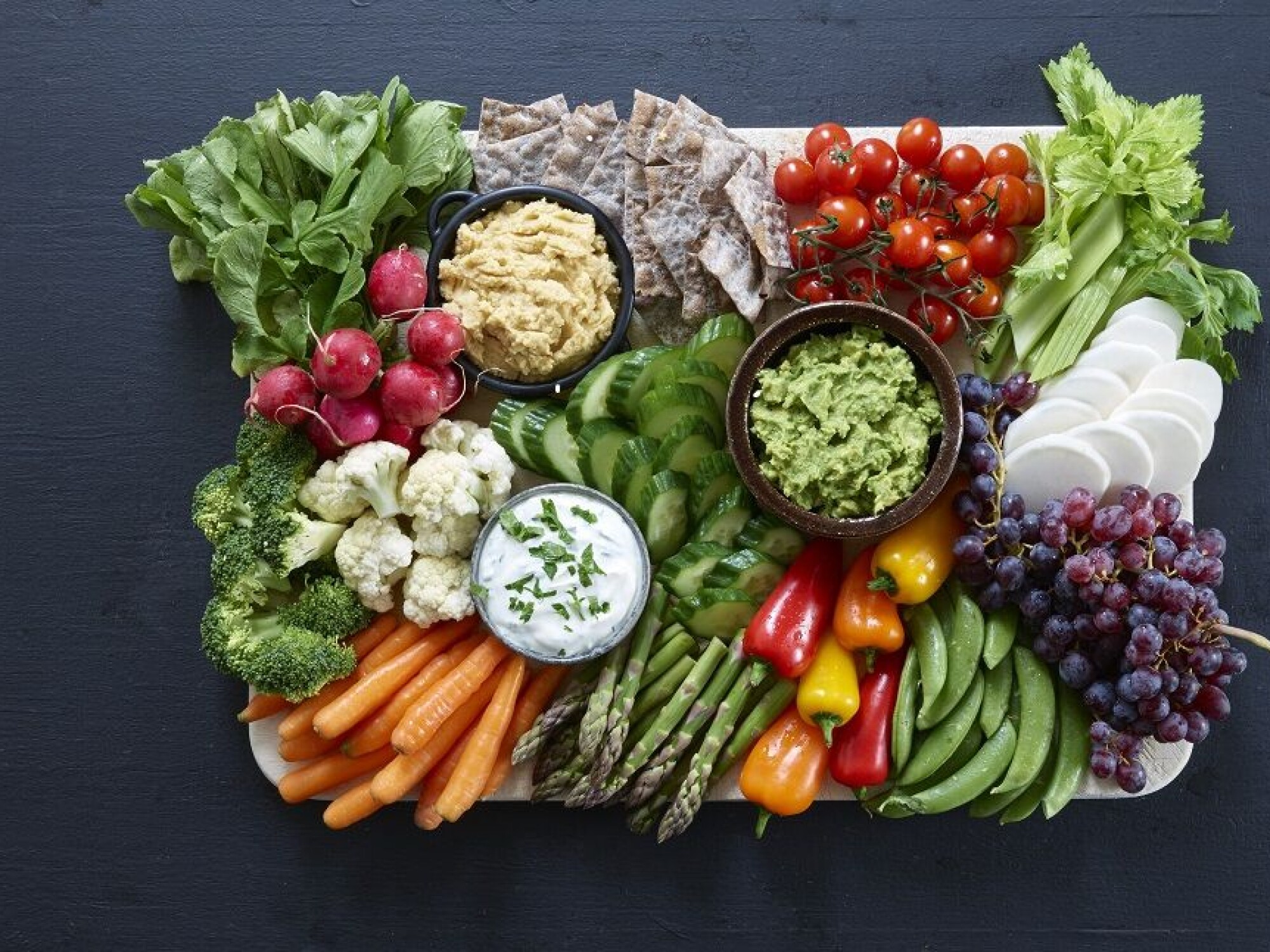 Friske grønnsaker servert med hummus, guacamole, og urtedressing